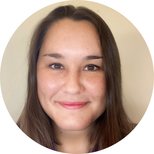 Khusbu Poudel has shoulder-length dark hair, wearing a gray blazer and a black top, is smiling against a blurred outdoor background with greenery.