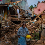 A woman walks past earthquake damaged houses in Nepal