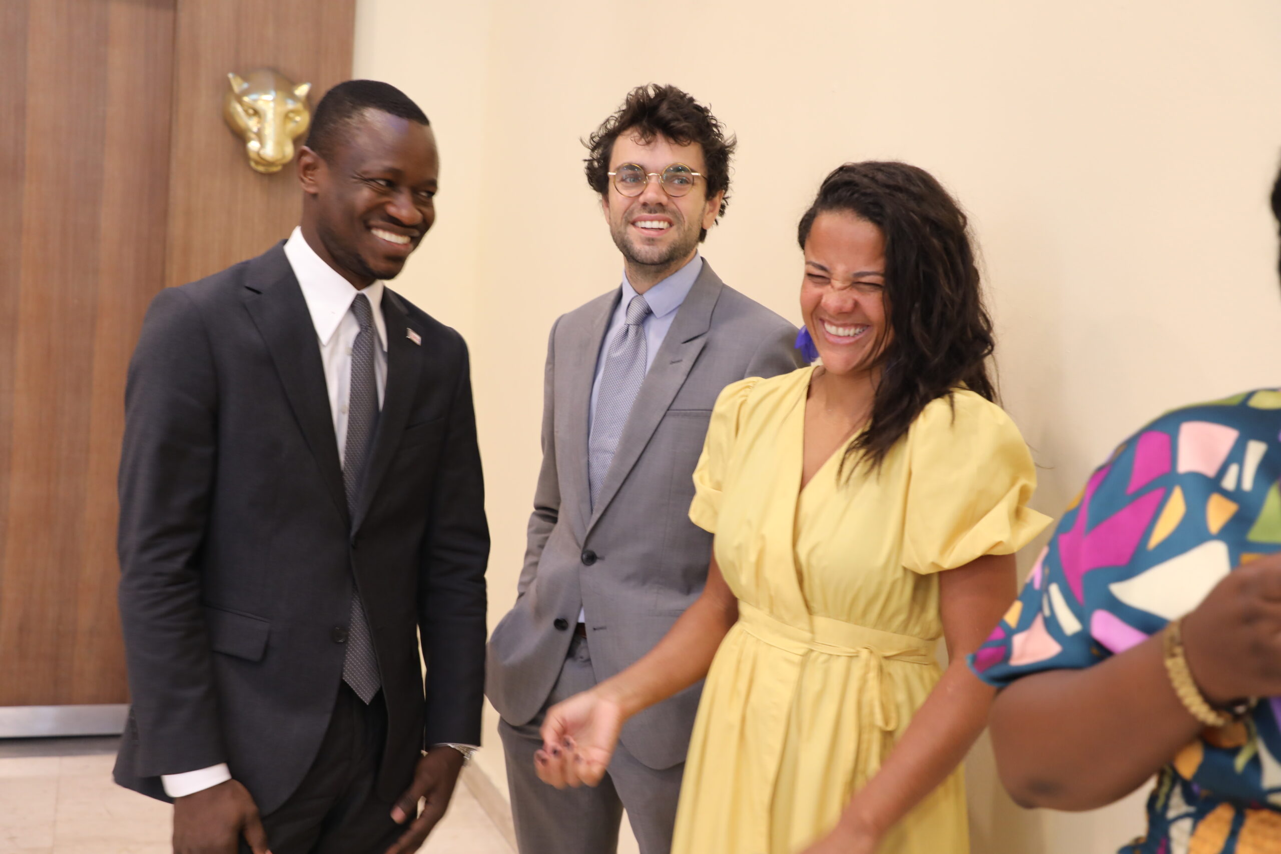 Three people smiling and standing together at an event, creating a warm and friendly atmosphere.