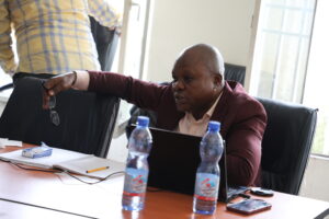 a man sitting at a table with a laptop and water bottles