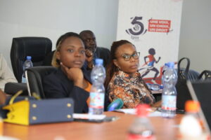 a group of people sitting at a classroom-style table and listening to a presenter