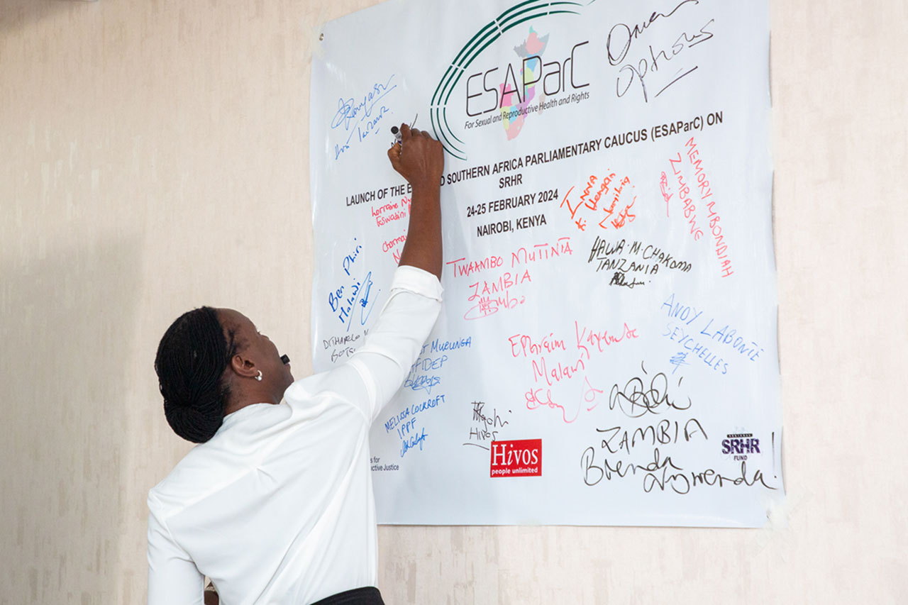 Dr. Angela Akol writes on a poster hanging on the wall.