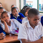 A classroom full of students, mostly girls, holding brochures.