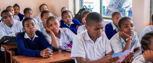 A classroom full of students, mostly girls, holding brochures.