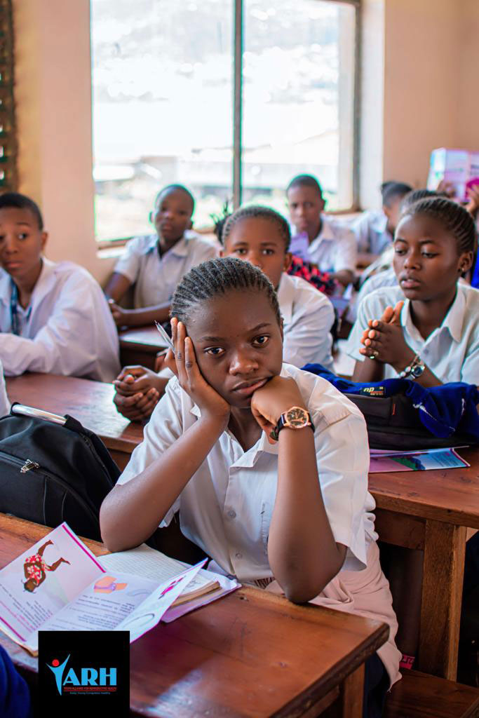 A classroom full of students, mostly girls, holding brochures.