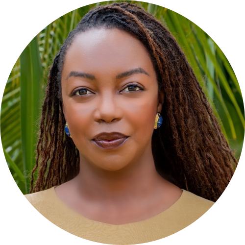 Fabiola Mizero, Regional Director Ipas Francophone Africa as A woman with long, brown, braided hair and blue earrings, wearing a beige top, stands outdoors in front of green palm leaves, smiling softly at the camera.