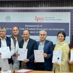 A group of men and women stand together indoors, holding documents and smiling at the camera. Behind them is a banner that reads, "Dissemination of Post-Abortion Family Planning Standards and Guidelines with the Ipas Pakistan logo at top.